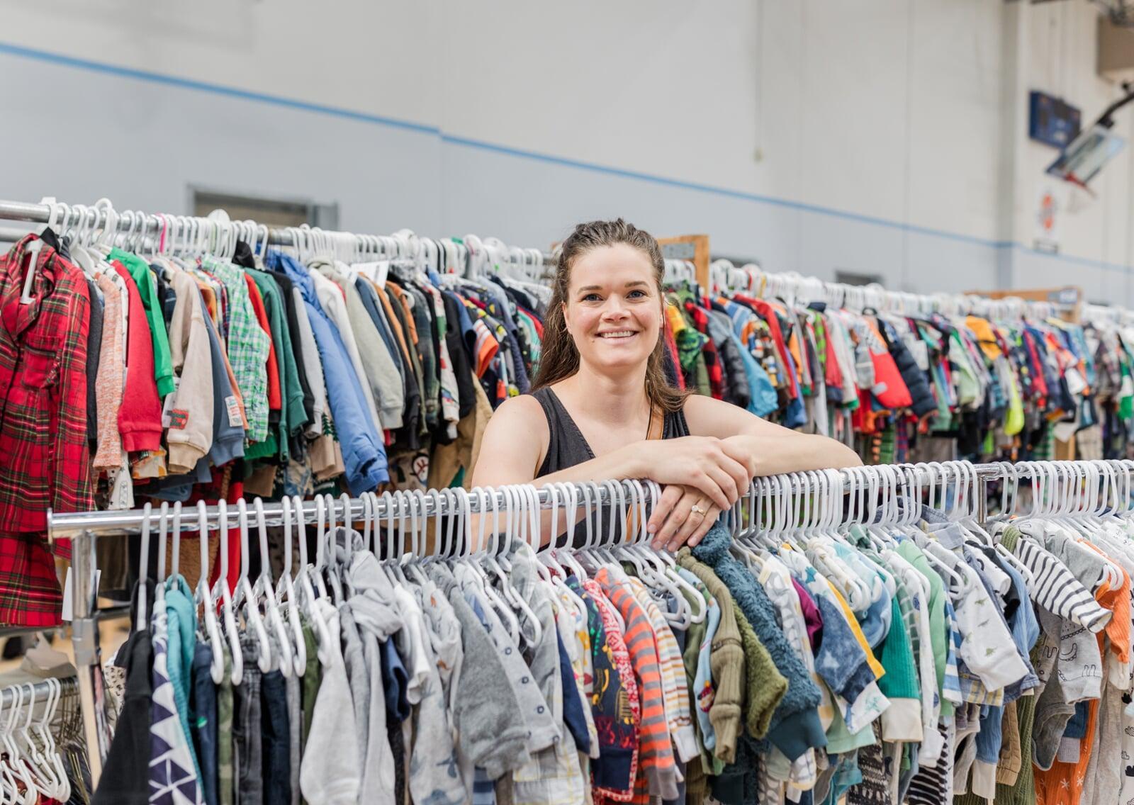 A mom and her four-year-old son stand with their masks and shopping bag in front of baskets of books and costumes.