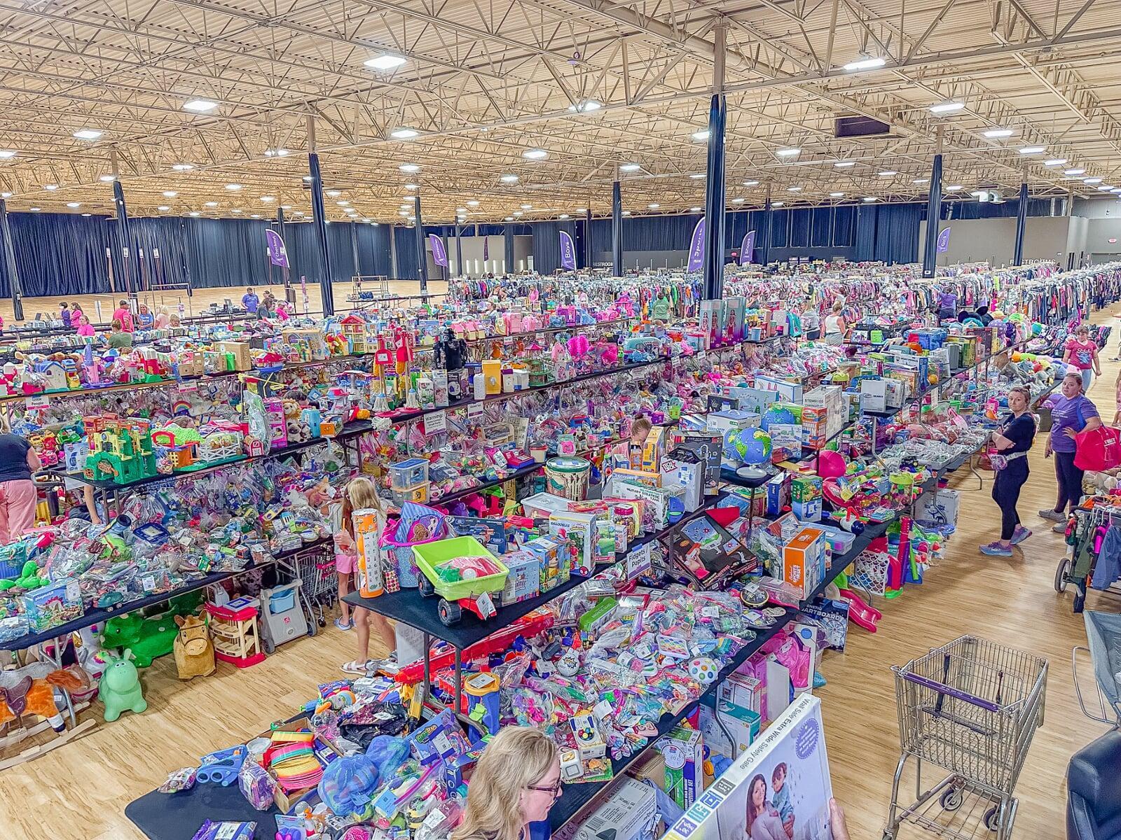 A mom and her four-year-old son stand with their masks and shopping bag in front of baskets of books and costumes.