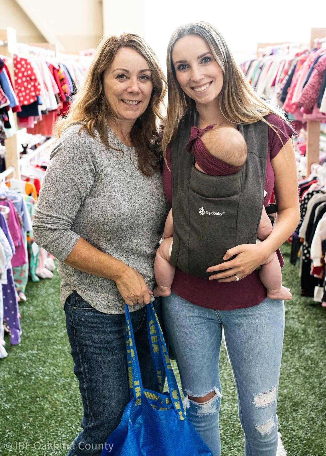 Beautiful mom holds two boys tops—one in each hand—as she shops the deals at her local sale.
