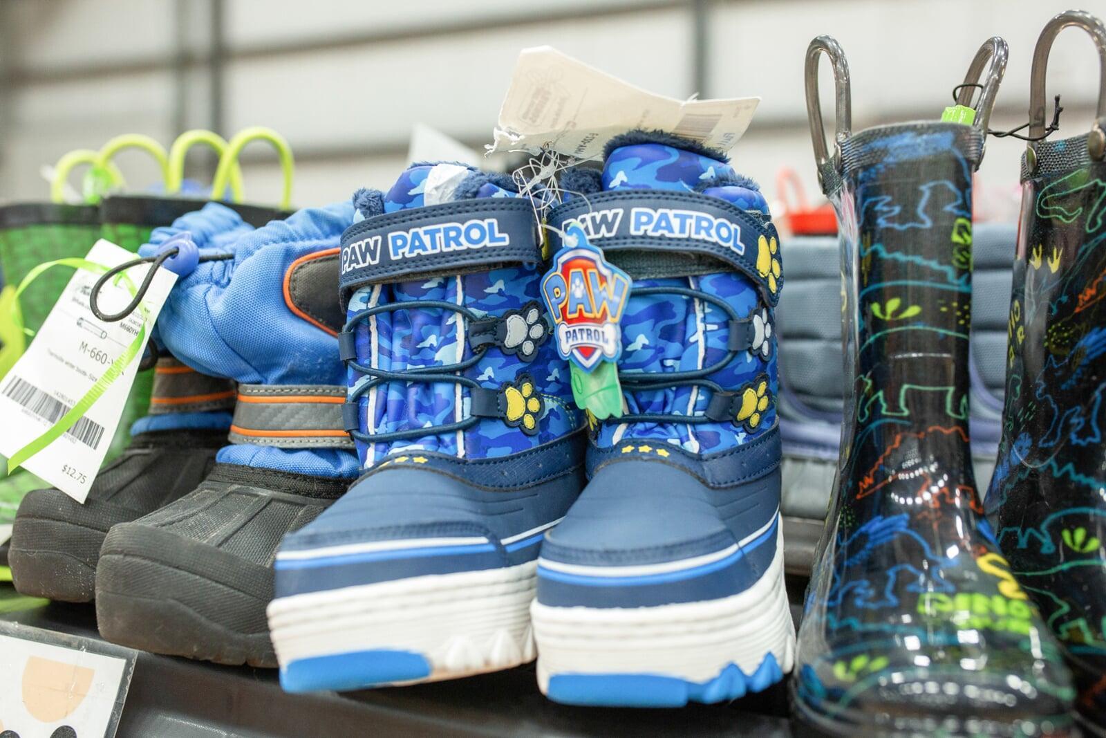 A mom and her two kids stand in the shoe section for a happy family photo.
