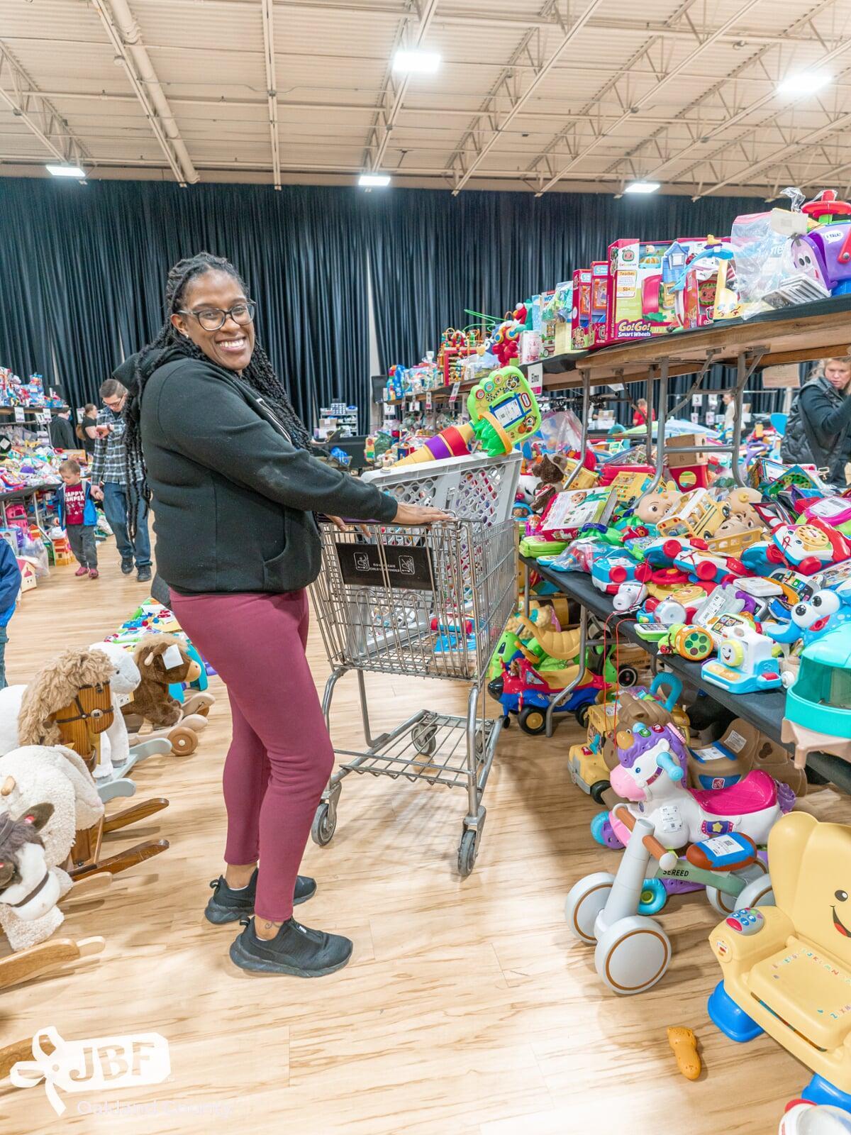 Mom holds hand up to show of rows and rows of clothing for sale at 50 to 90% off retail prices!