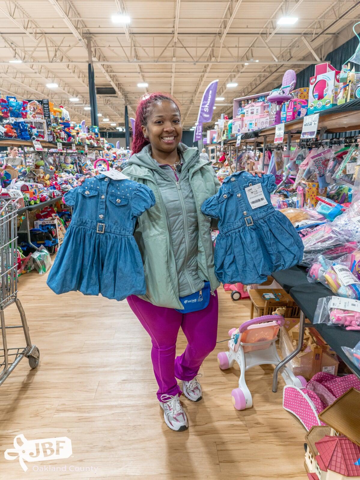 Three generations shop together at their local JBF sale. Mom carries baby in a baby carrier while grandmom stands behind them.
